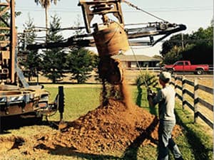 Soil removal during professional drilling service Technician clearing soil extracted during drilling operations