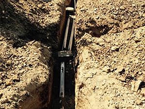 Repairing underground piping to prevent septic system issues Technician repairing a damaged underground pipe in an open trench
