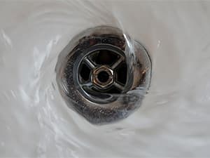 Proper water usage helps protect septic system performance Water flowing down a sink drain during everyday household use