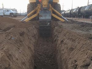Excavation for septic system installation using heavy machinery Heavy machinery excavating a trench for septic system installation