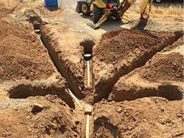 Septic distribution layout before backfilling Exposed septic distribution pipes branching into multiple trench lines