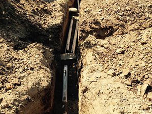 Repairing underground piping to prevent septic system issues Technician repairing a damaged underground pipe in an open trench