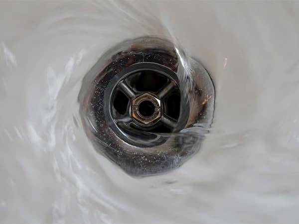 Proper water usage helps protect septic system performance Water flowing down a sink drain during everyday household use