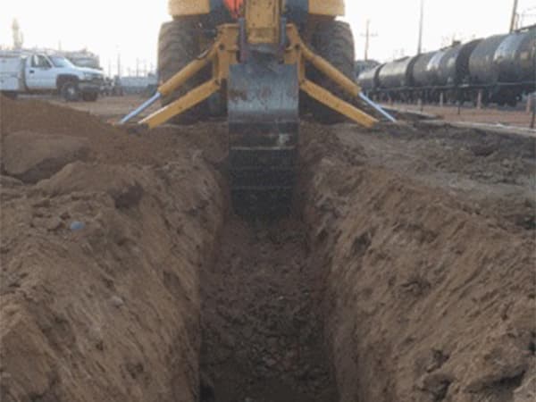 Excavation for septic system installation using heavy machinery Heavy machinery excavating a trench for septic system installation